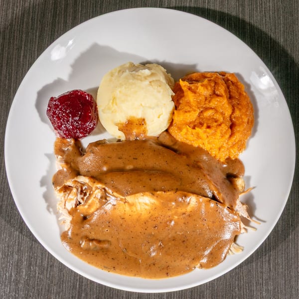 American Thanksgiving dinner with turkey, gravy, mashed potatoes, sweet potatoes, and cranberry sauce.