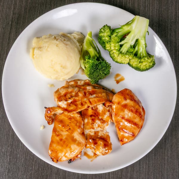 Grilled chicken with barbecue sauce, mashed potatoes, and steamed broccoli on a white plate.