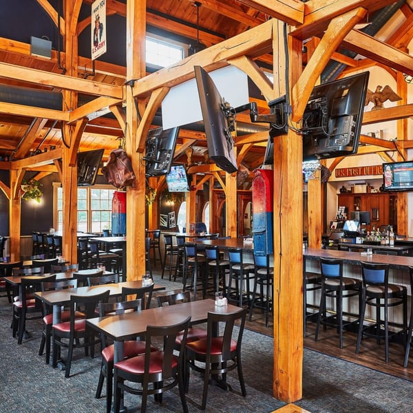 Spacious Post Office Pub dining room with wooden beams, tables, chairs, and a bar area.