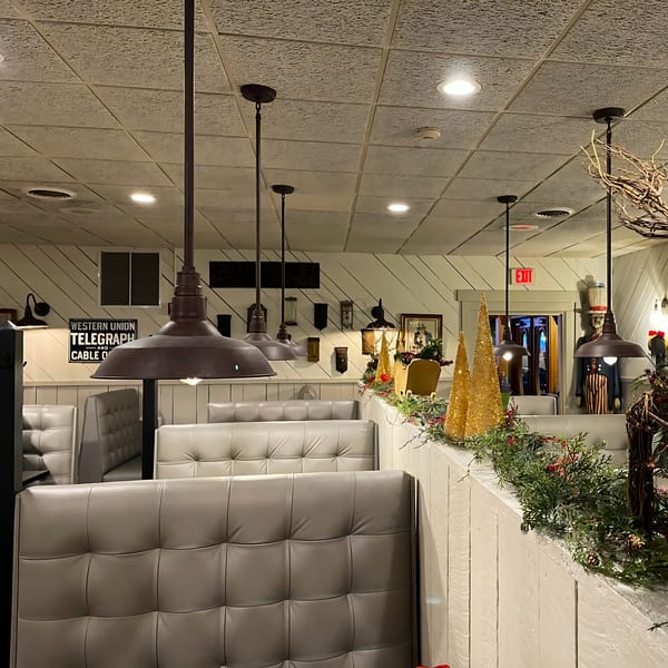 Cozy dining area at Post Office Pub with booth seating, industrial lighting, and festive decorations.